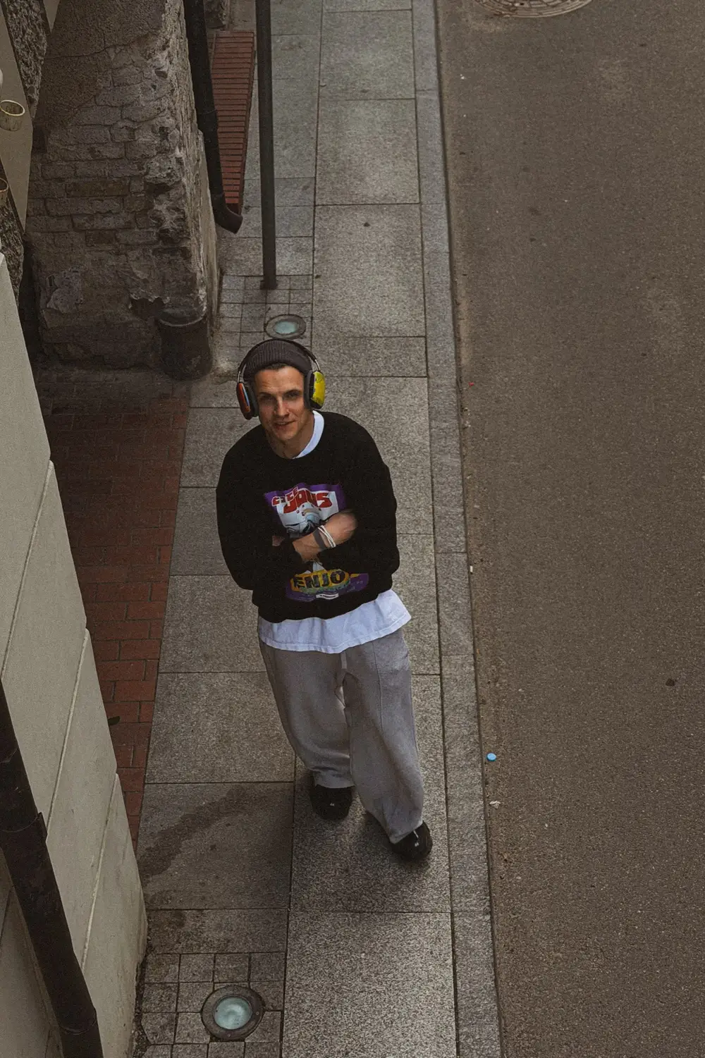 The figure walking toward the camera down a narrow alley, seen from above.