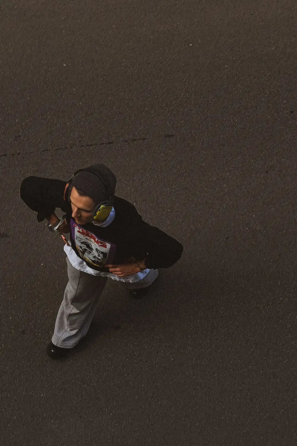A figure walking past a graffitied doorway, seen from above.